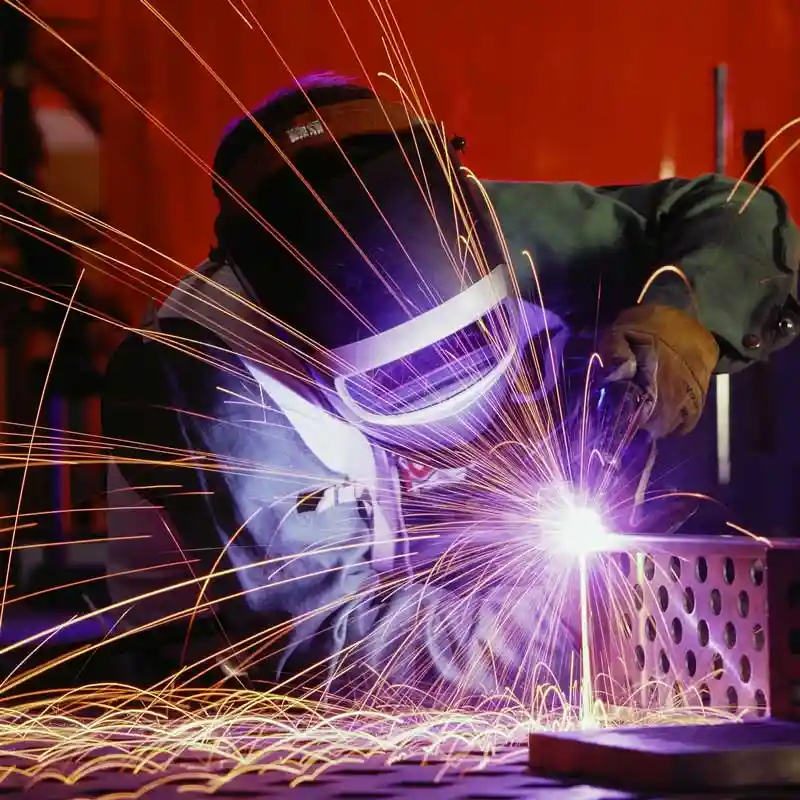 A welder welding metal with sparks flying